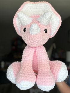 a pink and white crocheted teddy bear is held up by someone's hand