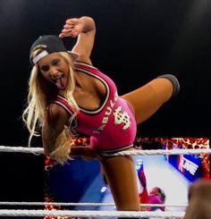 a woman in a pink wrestling outfit standing on one leg with her legs spread out