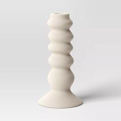 a tall white vase sitting on top of a table