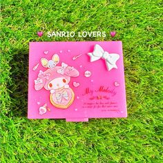 a pink card with an image of a cat and bow on it sitting in the grass