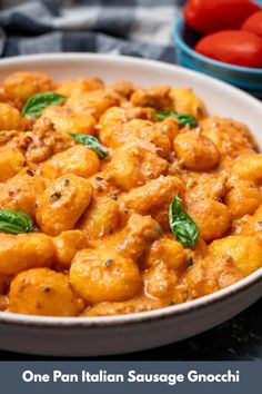 one pan italian sausage gnocchini in a white bowl with tomatoes and basil