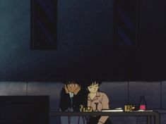 two people sitting at a table in the dark