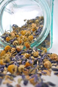 a jar filled with dried flowers next to a pile of other flowery things in it