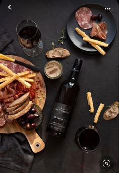 a table topped with two plates of food and a bottle of wine next to it