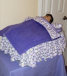 a woman laying on top of a bed covered in purple sheets and pillows with her head resting on the pillow