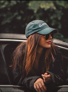 a woman sitting in the back of a car wearing sunglasses and a hat on top of her head