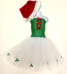 🎄 Beautiful girl's, Christmas themed tutu dress.  🎄Handmade, fluffy tutu dress with white tulle skirt and Holly edging detail.  Green elasticated body with red bow detail to front.  Comes with a matching Santa hat.  A fun, seasonal addition to any girl's wardrobe.  🎄Suitable for child 2-7 years of age, but can do, larger if required.  🎄Beautiful, bespoke, delicately handmade, child's tutu. All tulle used has been tested and conforms to EU safety standards, EN 71-2 flammability and EN 71-3 Mi White Fitted Tutu Dress For Christmas, White Tulle Skirt, Christmas Tutu, Xmas Dress, Santa Dress, Kids Tutu, Dress Tutu, Dress Handmade, White Tulle