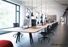 a long table with chairs and computers on it in an open room next to large windows