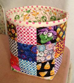 a colorful patchwork basket sitting on top of a wooden table next to a wall