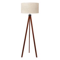 a wooden tripod floor lamp with a white linen shade on the top and brown legs