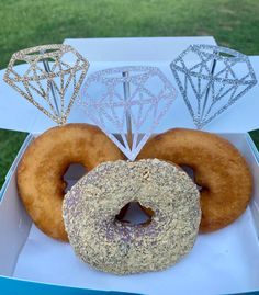 three donuts in a box with diamond decorations