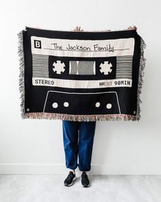 a person holding up a black and white blanket with an old fashioned cassette tape on it