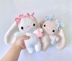 two crocheted stuffed animals being held in the air by someone's hand