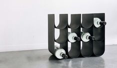 the skateboard rack is made out of black and white plastic tubes with wheels attached to it