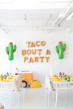 a party with taco bouta and cactus decorations on the wall, tables and chairs