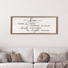 a living room with a white couch and wooden framed wall art above it that reads home is where love resides