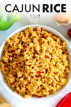 a white bowl filled with rice next to some red peppers and garlic on a table