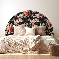 a bed with flowers on the headboard and pillows in front of it, next to a wicker basket