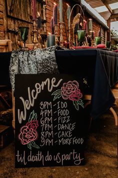 a sign that is sitting on the ground in front of a table with flowers and candles