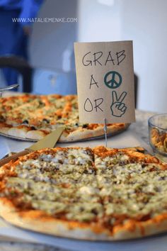 two pizzas sitting on top of a table with a sign that says grab a slice