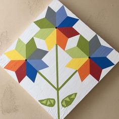 a colorful flower painted on top of a white piece of paper with green leaves in the center