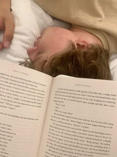 a man laying in bed reading a book with his head on top of an open book