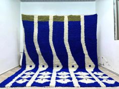 a crocheted blue and white blanket sitting on top of a wooden floor next to a window