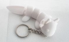 a white plastic animal keychain sitting on top of a white cloth covered surface