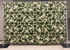 white flowers are arranged on a wall in an office building or conference room, as well as greenery