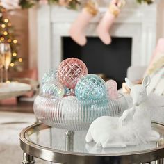 a glass table with ornaments on it in front of a fireplace