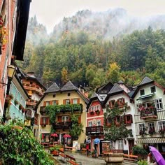 a woman with an umbrella walks down a cobblestone street lined with houses in the mountains