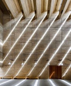 an empty room with wooden walls and beams on the ceiling is lit by sunlight streaming through the windows