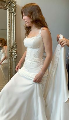 a woman in a wedding dress is looking at herself in the mirror and holding her jacket