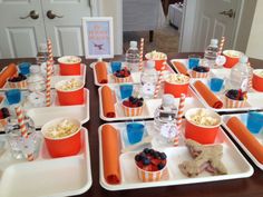 a table topped with cups and trays filled with dessert items on top of plates