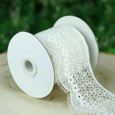 two rolls of white lace sitting on top of a wooden table