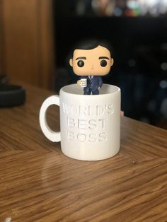 a small figurine is sitting in a coffee cup that says world's best boss