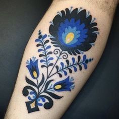 a blue and black flower tattoo on the arm