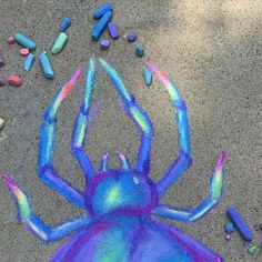 a drawing of a spider on the ground with crayons all around it,