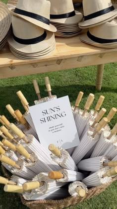 hats are arranged in a basket on the grass near a sign that reads, sun's shining