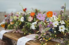 a wooden table topped with lots of different types of flowers