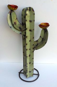 a green cactus with two red flowers on it's top and the other side