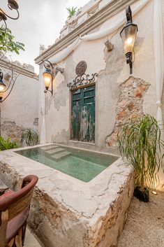 an outdoor hot tub in front of a building with a door and window above it