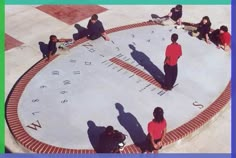 several people sitting on the ground in front of a clock