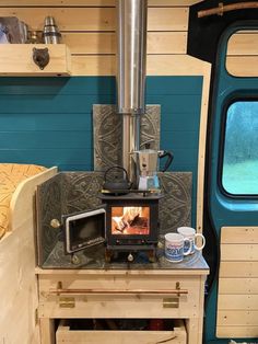 a stove top oven sitting on top of a wooden table next to a cup filled with coffee