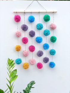 a colorful wall hanging with pom - poms