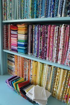 the shelves are filled with many different colored fabrics and quilting material, all stacked together