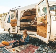 a woman sitting on the ground in front of a van