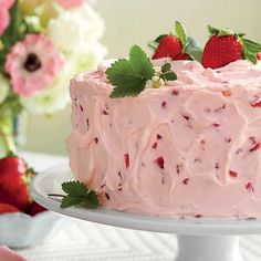 a strawberry cake with frosting and fresh strawberries on the top is ready to be eaten