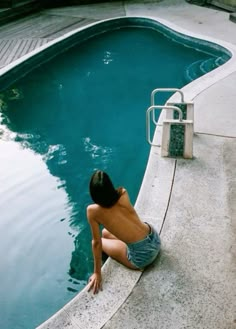 a person sitting on the edge of a swimming pool