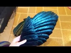 a person is holding a blue feather in their hand while they are on the floor